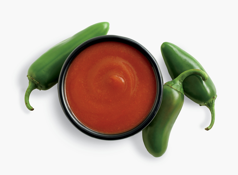 Whole jalapenos surround side ramekin of jalapeno hot sauce