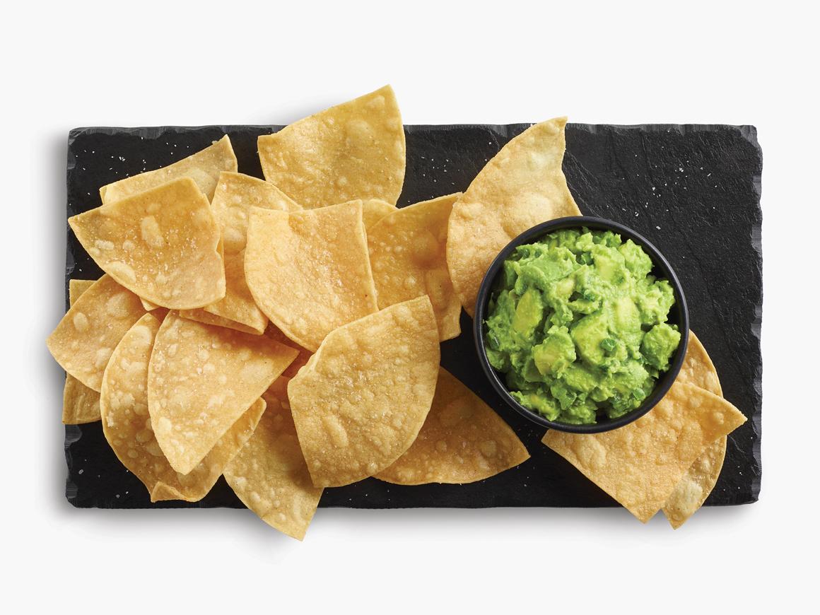 Chips on a plate with a cup of guacamole