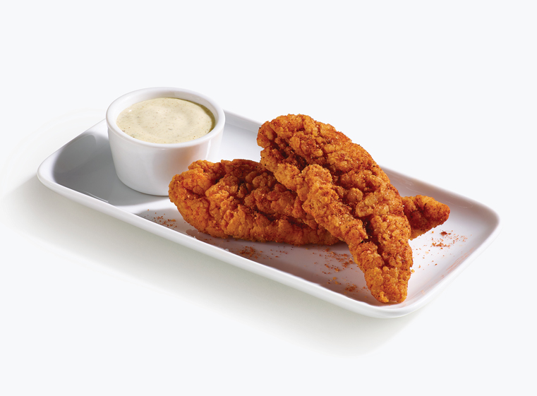 two spicy tenders on a white plate with baja lime sauce in a white ramekin.