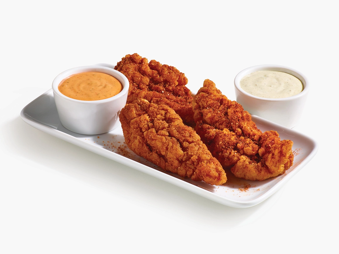 3 spicy tenders on a white plate with loco sauce and baja lime sauce in white ramekins